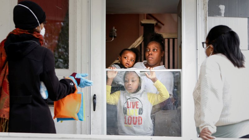 A family in Rochester, N.Y., receives a coronavirus survival kit Oct. 17, 2020, as part of a door-to-door outreach program to help the Black community understand the vaccine trial. (CNS photo/Lindsay DeDario, Reuters)