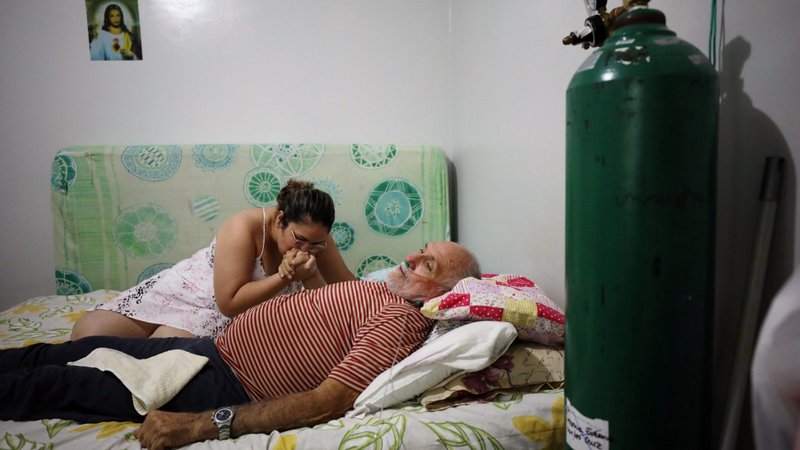 Osmar Magalhaes, 68, who suffers from COVID-19, is helped by his daughter Karoline Magalhaes at his home, where he set up his own emergency ward with air tanks due to lack of oxygen in the public health system, in Manaus, Brazil, Jan. 20, 2021. (CNS photo/Bruno Kelly, Reuters)