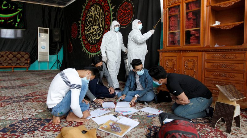 Workers disinfect the interior of a mosque to prevent the spread of the coronavirus disease as students, wearing masks, continue to study in the holy city of Najaf, Iraq, Feb. 15, 2021. As part of COVID-19 precautions, the Iraqi government has ordered the closure of mosques and churches "until further notice." Pope Francis is scheduled to visit Iraq March 5-8 and has events planned in churches each day. (CNS photo/Alaa Al-Marjani, Reuters)