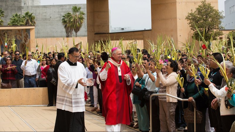 Los Angeles Archbishop Jose H. Gomez sprinkles holy water on people holding palm fronds during Palm Sunday Mass at the Cathedral of Our Lady of the Angels in Los Angeles in this April 13, 2014, file photo. As the COVID-19 pandemic nears its first full year, the Vatican Congregation for Divine Worship and the Sacraments reminded bishops that the guidelines it issued last year for celebrating the Triduum and Easter liturgies would still be valid this year. (Victor Alemán)