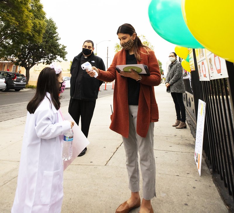 A Resurrection School student gets her temperature checked before heading into the building for class. (Victor Alemán)