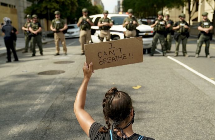 A woman in Washington holds a placard near law enforcement officers June 6, 2020. Demonstrations continued after a white police officer in Minnesota was caught on a bystander's video May 25 pressing his knee into the neck of George Floyd, a Black man, who was later pronounced dead at a hospital. (Erin Scott/ Reuters, via CNS).
