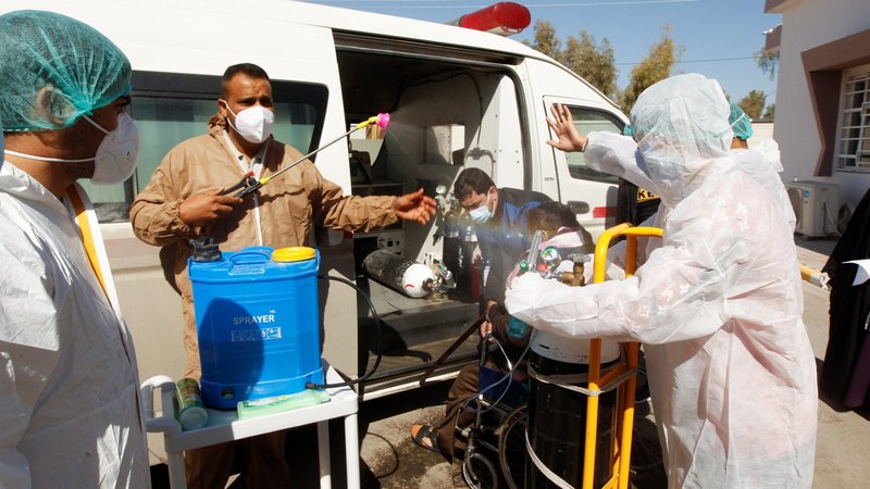 A medical team member sprays disinfectant on a person believed to have the coronavirus as he is being brought to a hospital in the holy city of Najaf, Iraq, Feb. 25, 2021. (CNS photo/Alaa Al-Marjani, Reuters)
