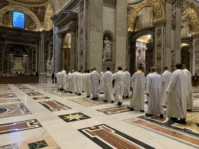 Priests in St. Peter's Basilica process to the altar where St. John Paul II is buried at the Vatican on Feb. 13, 2020. Dozens of priests concelebrate an early morning Mass at the tomb every Thursday. (CNS photo/Cindy Wooden)