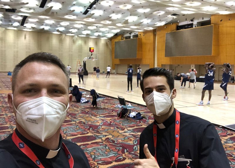 Deacon Austin Bosse, left, a seminarian from the Diocese of Peoria, Ill., takes a selfie with Brian Florin, a seminarian from the Diocese of Fort Wayne-South Bend, Ind., as the Mount St. Mary's Mountaineers basketball team works out in the background in Indiana March 16, 2021. Deacon Bosse is the chaplain and Florin is assistant chaplain for the Maryland team. (CNS photo/Deacon Austin Bosse via The Catholic Post)