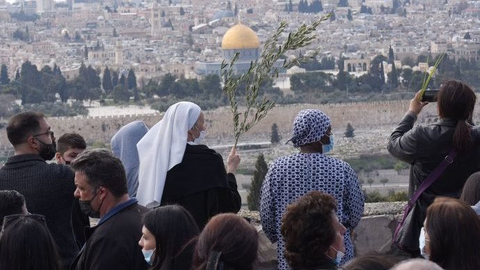 A nun holds an olive branch as she and others stop along the traditional path that Jesus took on his last entry into Jerusalem during the Palm Sunday procession on the Mount of Olives in Jerusalem March 28, 2020. (Debbie Hill/CNS.)