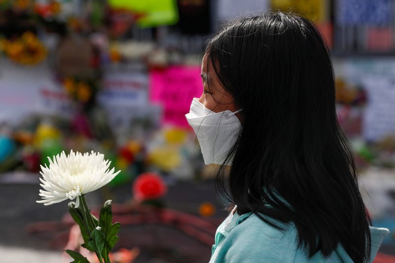 A girl in Atlanta holds a flower March 21 at a vigil outside one of the three day spas targeted in a series of deadly shootings March 16 in metro Atlanta. (CNS/Shannon Stapleton, Reuters)