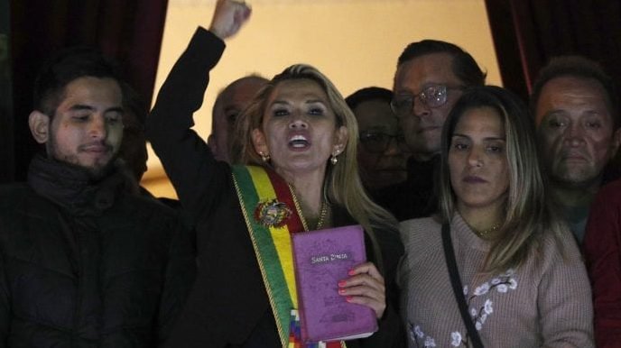 In this Nov. 12, 2019, AP file photo, the Senate's second vice president and opposition politician Jeanine Añez, center, wearing the presidential sash and carrying a Bible, addresses the crowd from the balcony of the Quemado palace after she declared herself interim president of the country, in La Paz, Bolivia. (Juan Karita/AP.)