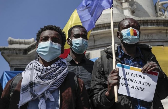 A Chadian man living in France holds the national flag and a placard that reads: “The people of Chad have a say'" during a protest in Paris, Sunday, April 25, 2021. The protesters denounced the nomination of Chadian President Idriss Deby Itno 's son to assume the interim presidency after his father’s death, which they called "monarchization." (Lewis Joly/AP via Crux)