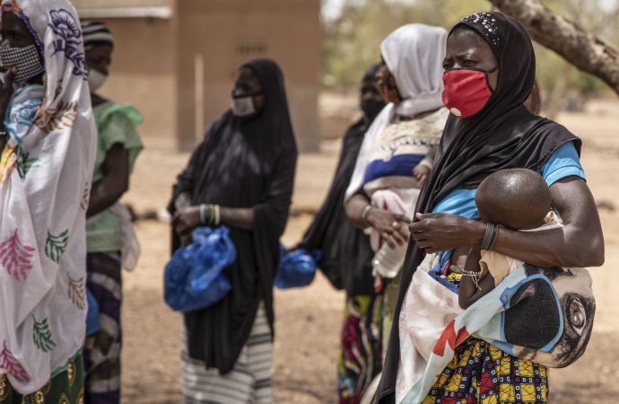 A displaced woman holds her child outside a school while waiting with others to receive food being distributed by Catholic Relief Services in Kaya, Burkina Faso. Catholic and Muslim leaders are working jointly to deter youth from terrorist violence in Africa's Sahel region. (Olympia de Maismont/Catholic Relief Services via CNS)