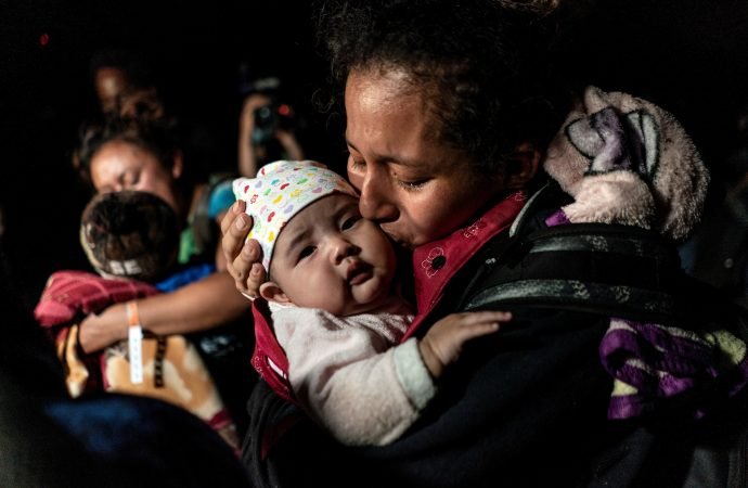 A mother from Guatemala seeking asylum in the U.S. kisses her 3-month-old baby while waiting to be escorted by Border Patrol agents in Roma, Texas, April 7, 2021, after crossing the Rio Grande into the United States. (Go Nakamura/Reuters, via CNS)