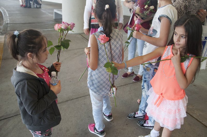 Heba Ibrahim, 8, left, the youngest daughter in a family of Kurdish refugees, receives a rose from a friend of the family in Nashville, Tenn. Aug. 30, 2016. The girl's family had been in Turkey after fleeing Syria's civil war and was now relocating to the U.S. Caseworkers from Catholic Charities of Tennessee also were on hand to greet the refugees and will offer case management services to the family as they resettle in the U.S. (CNS photo/Theresa Laurence, Tennessee Register)
