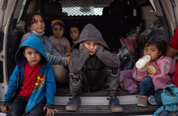 Migrant children from Central America take refuge from the rain in the back of a U.S. Border Patrol vehicle in Penitas, Texas, March 14, 2021, as they await to be transported after crossing the Rio Grande into the United States. (Adrees Latif/ Reuters, via CNS)