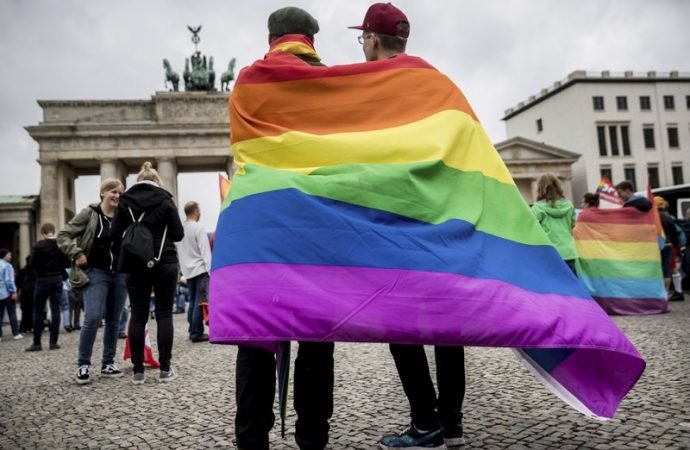 In this June 30, 2017 file photo, men with rainbow flags stand in front of the Brandenburg Gate in Berlin. (Michael Kappeler/dpa via AP/Crux)