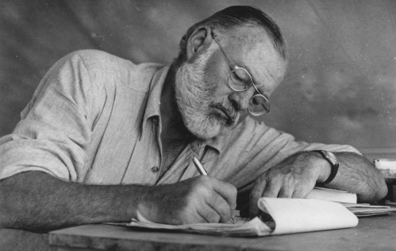 Ernest Hemingway writing while at his campsite in Kenya, circa 1953. (Look Magazine/Wikimedia Commons)
