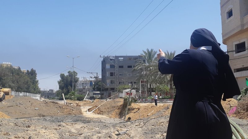 Sister Nabila Saleh, principal at the Rosary Sisters School in Gaza, gestures towards the damaged road in front of her school compound and convent May 12, 2021. The damage was caused by Israeli airstrikes. (CNS photo/courtesy Holy Family Catholic Parish, Gaza) Editors: best quality available.