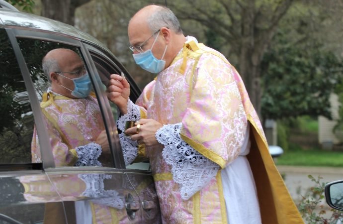 Deacon Peter Tonon distributes holy Communion in the parking lot of St. Ann Catholic Church in Charlotte, N.C., March 22, 2020, amid the coronavirus pandemic. (CNS photo/SueAnn Howell, Catholic News Herald)