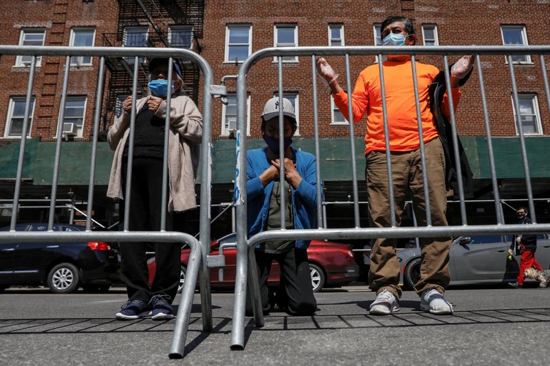 People in the Queens borough of New York City pray outside St. Bartholomew Church May 15, 2020, during the coronavirus pandemic. (CNS photo/Brendan McDermid, Reuters)