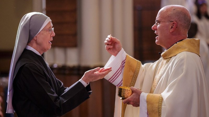 Sister Loraine Marie Maguire, mother provincial of the Denver-based Little Sisters of the Poor, receives Communion from Bishop Kevin C. Rhoades of Fort Wayne-South Bend, Ind., during Mass at the Basilica of the Sacred Heart the University of Notre Dame in Indiana April 9. (CNS photo/Peter Ringenberg, Notre Dame Center for Ethics and Culture)