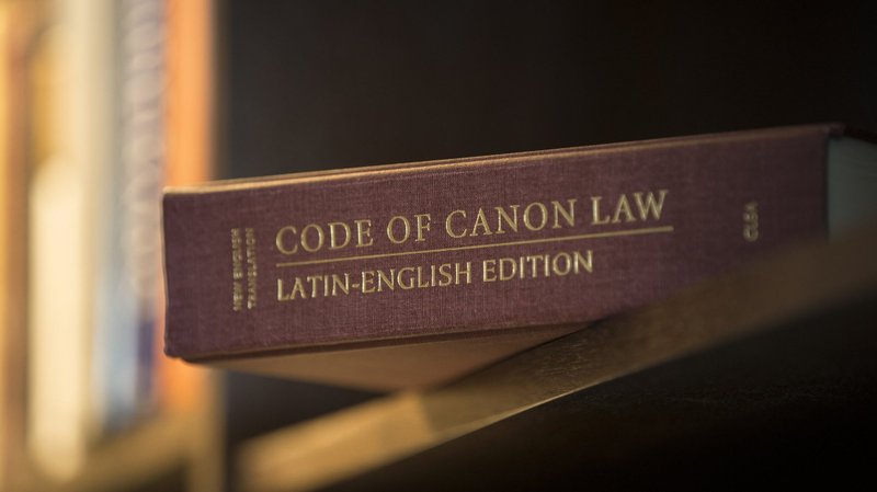 A Latin-English edition of the Code of Canon Law is pictured on a bookshelf. New canon law provisions approved by Pope Francis are expected to help the Catholic Church safeguard against abuse. (CNS photo/Nancy Phelan Wiechec)