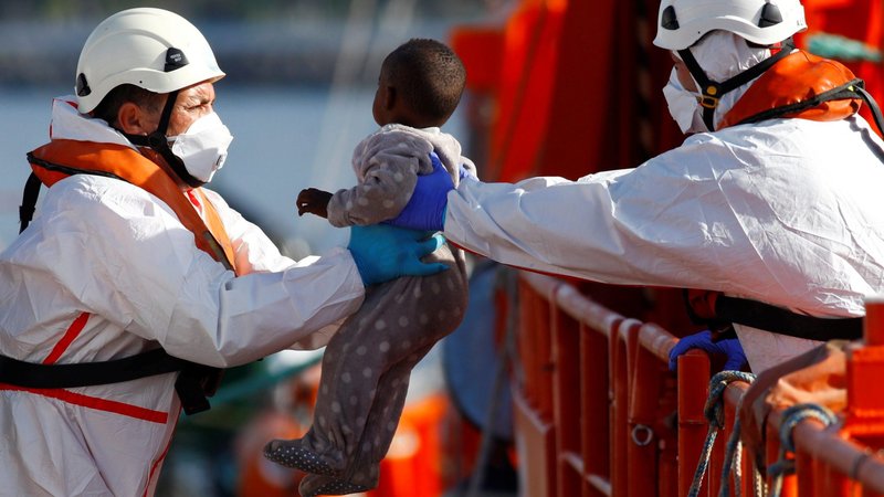 Rescuers help a migrant child disembark from a Spanish coast guard vessel, in the port of Arguineguin, on the island of Gran Canaria, Spain June 4, 2021. (CNS photo/Borja Suarez, Reuters)