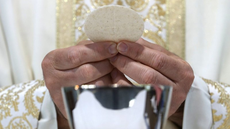 A priest holds the Eucharist in this illustration. (CNS photo/Bob Roller)