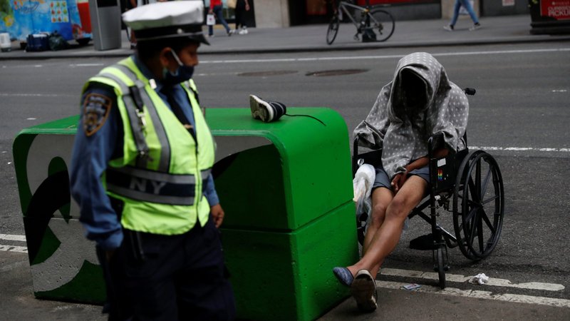 A man in New York City sits in a wheelchair as a NYPD traffic officer passes by near Times Square June 11, 2021. (CNS photo/Shannon Stapleton, Reuters)