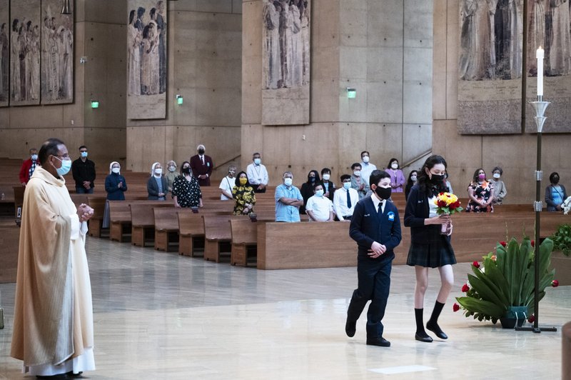 During Mass, 8th grade students from Dolores Mission School in Boyle Heights brought flowers to the foot of the new tapestry honoring the Blessed Virgin Mary in the Cathedral sanctuary. (Victor Alemán)