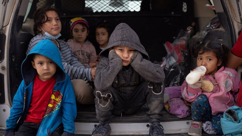 Migrant children from Central America take refuge from the rain in the back of a U.S. Border Patrol vehicle in Penitas, Texas, March 14, 2021, as they await to be transported after crossing the Rio Grande into the United States. (CNS photo/Adrees Latif, Reuters)