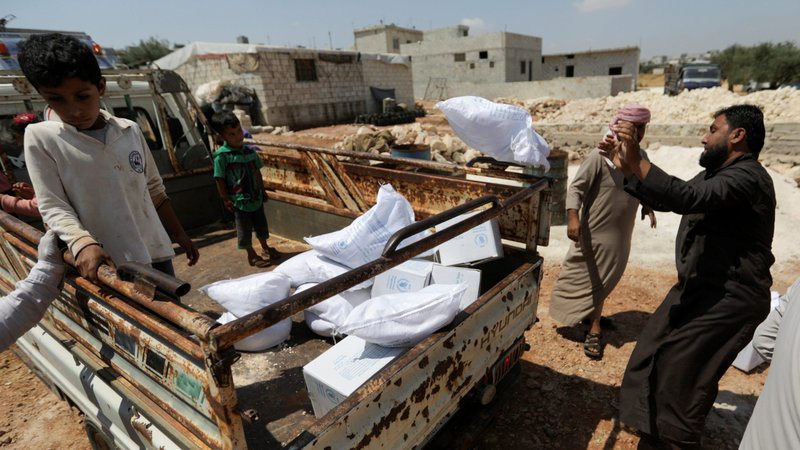 An internally displaced Syrian boy stands next to boxes of humanitarian aid at the back of a truck in the opposition-held Idlib, Syria, June 9, 2021. (CNS photo/Khalil Ashawi, Reuters)