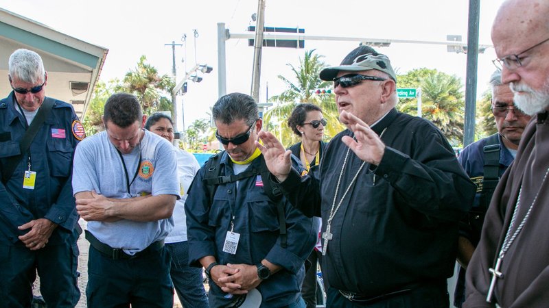 Archbishop Thomas G. Wenski of Miami blesses search and rescue personnel in Surfside, Fla., July 2, 2021, after arriving at the site of the collapsed Champlain Towers South with Boston Cardinal Sean P. O'Malley. The archbishop and cardinal prayed at and blessed the site while also visiting, praying with, and blessing the search and rescue crews who have been working 24/7 since the collapse. (CNS photo/Ana Rodriguez-Soto, Florida Catholic)