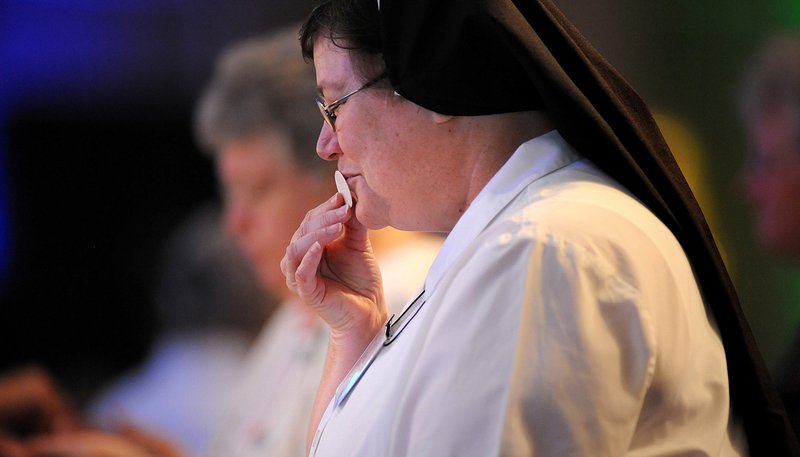 Sister Carol Bredenkamp kisses the host as she receives Communion during a conference in St. Louis in 2012. (Sid Hastings/CNS)