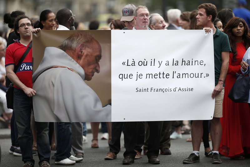 People hold a banner with a picture of French priest Father Jacques Hamel, which reads, "Where there is hatred, let me sow love," after a 2016 Mass at the Notre Dame Cathedral in Paris. Father Jacques Hamel was killed in an attack on a church at Saint-Etienne-du-Rouvray near Rouen by assailants linked to Islamic State groups. (CNS/Benoit Tessier, Reuters)
