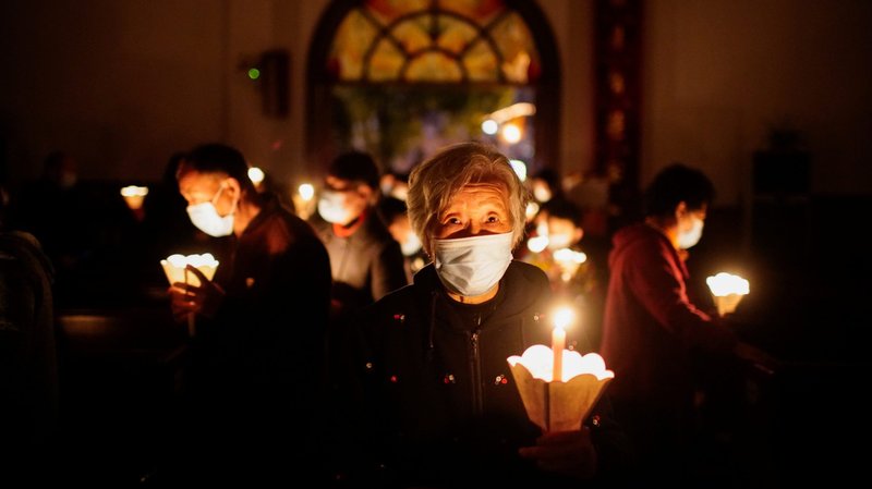 Worshippers holding candles and wearing protective masks pray during the Easter Vigil in Shanghai April 3, 2021, during the COVID-19 pandemic. In an interview published Aug. 12 with the Italian news site La Voce del Nordest, Cardinal Pietro Parolin, Vatican secretary of state, said that while the Holy See continues to dialogue with the Chinese government, the church continues to be proud of Catholics in the country for their "witness of faith." (CNS photo/Aly Song, Reuters)