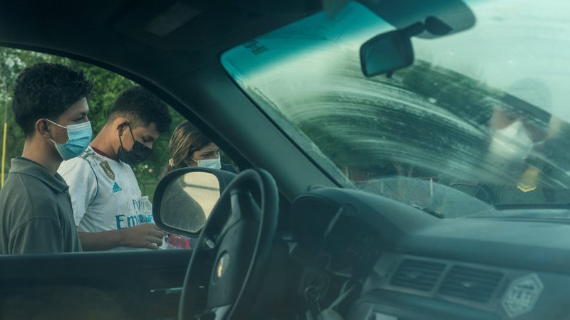 Migrants from Central America in Penitas, Texas, are seen next to a car as they are processed by a U.S. Border Patrol agent after crossing the Rio Grande July 8, 2021. (CNS photo/Go Nakamura, Reuters)