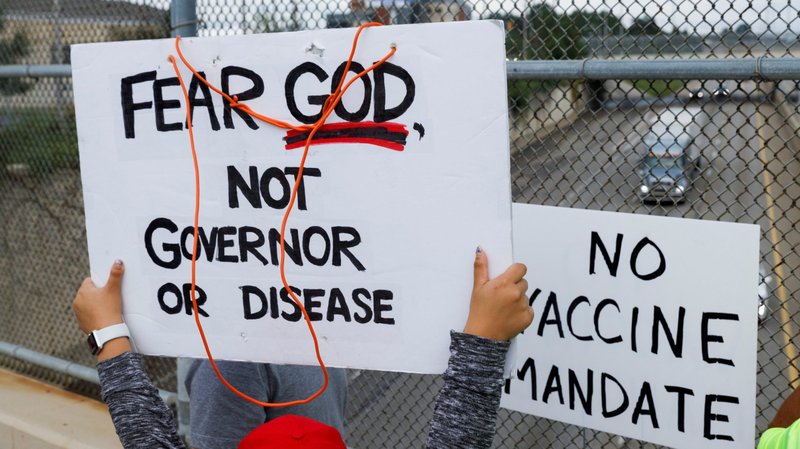 People raise signs against a chain-link fence to show drivers on Ohio State Route 8 during a protest against the COVID-19 vaccine mandates at Summa Health Hospital in Akron, Ohio, Aug. 16, 2021. (CNS/Stephen Zenner, Reuters)
