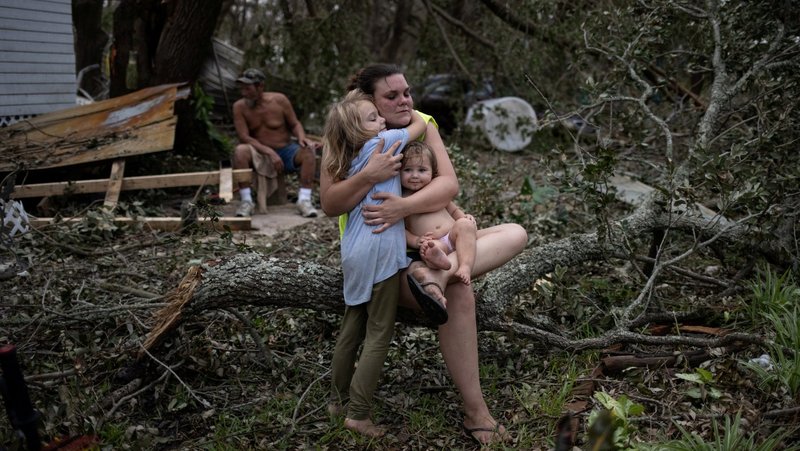 In the aftermath of Hurricane Ida, Tiffany Miller of Golden Meadow, La., embraces her daughter Desilynn, 6, outside their home Sept. 1, 2021, as she holds her 1-year-old godchild, Charleigh. (CNS photo/Adrees Latif, Reuters)