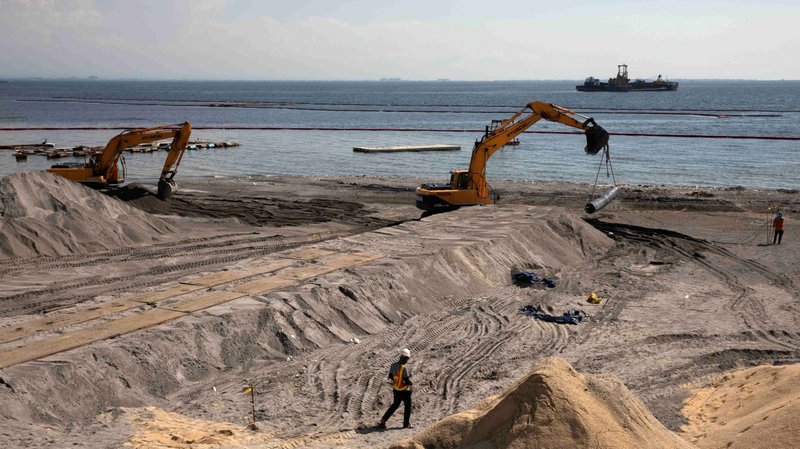 A worker stands on artificial sand or crushed dolomite, dumped on a portion of Manila Bay Sept. 4, 2020, as part of the Philippine government's efforts to rehabilitate and beautify the coastline. Two Philippine bishops are raising the alarm about rising sea levels that make the Philippine capital one of the fastest-sinking cities in the world. (CNS photo/Eloisa Lopez, Reuters)