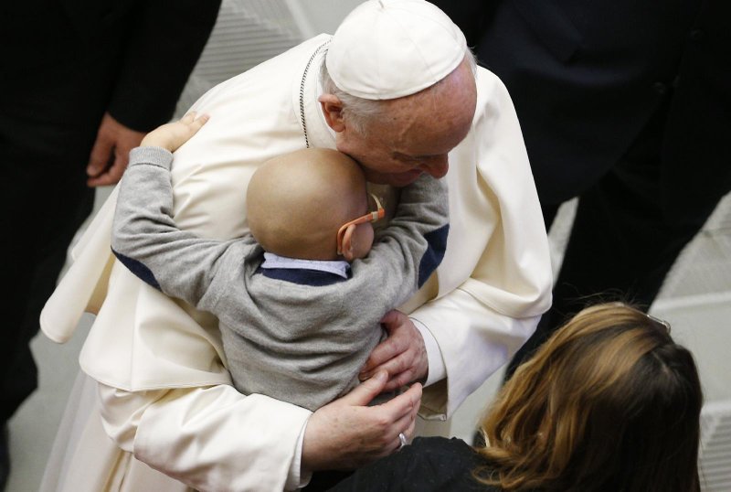Pope Francis is embraced by a child during his general audience in the Paul VI hall at the Vatican Oct. 27, 2021. (CNS photo/Paul Haring)