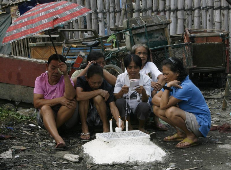 Relatives pray at the tomb of a loved one in a public cemetery in Navotas city, north of Manila, Philippines, in this Nov. 1, 2011, file photo. With the continuing pandemic, the Vatican has again extended throughout all of November the opportunity to receive a plenary indulgence for visiting a cemetery to pray for the dead. (CNS photo/Romeo Ranoco, Reuters)