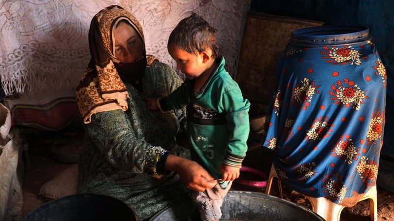 Fawza Umri helps her son put on clothes after being bathed inside their tent at Atmeh camp, near the Turkish border in Syria, June 13, 2020. Humanitarian groups have accused Turkey of "weaponing water" in the northeast region of Syria. (CNS photo/Khalil Ashawi, Reuters)