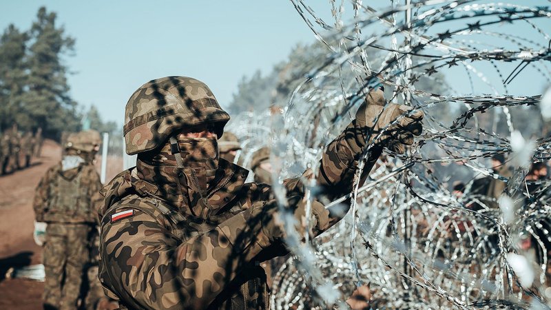 A Polish soldier installs barbed wire on the Poland-Belarus border near Kuznica, Poland, Nov. 9, 2021. Poland deployed 15,000 troops with razor wire and tear gas and announced plans for a 65-mile border wall after stranded migrants, mostly from Asia and the Middle East, amassed at the border. (CNS photo/Irek Dorozanski. DWOT handout via Reuters)
