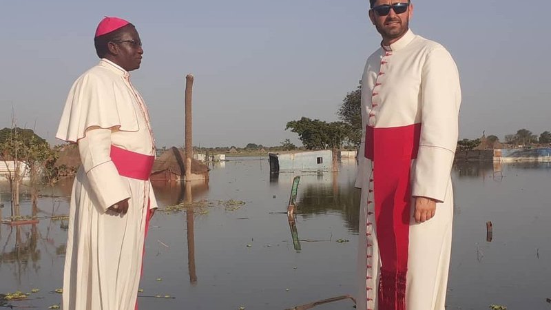 Bishop Stephen Nyodho Ador Majwok of Malakal, South Sudan, and Msgr. Ionut Paul Strejac, chargé d'affaires at the Vatican Embassy in South Sudan, stand in Bentiu, where ongoing flooding has submerged buildings, homes and markets. Bishop Majwok has called for support, as floods continued to devastate his diocese, creating a complex web of challenges. (CNS photo/courtesy Bishop Majwok)