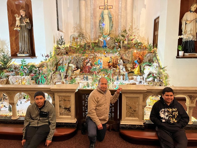 Jose Fuentes and his two sons with the Nativity scene they built at Our Lady of Sorrows in Santa Barbara. (Maria Ortiz)