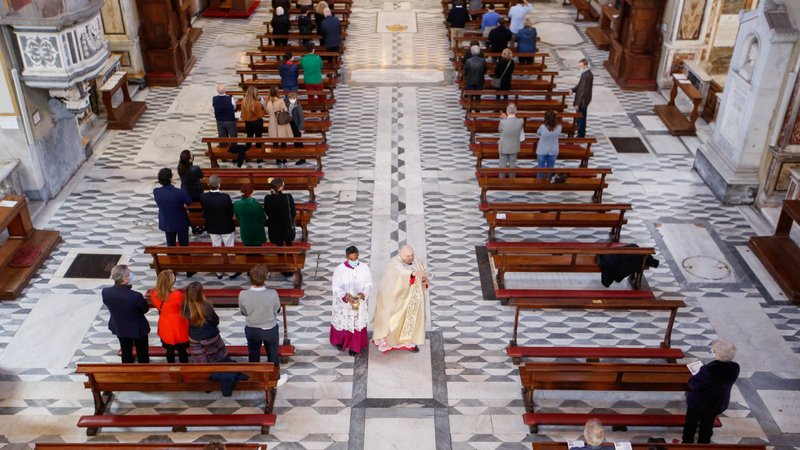 A priest walks past a limited number of faithful in attendance during an Easter Mass in the San Lorenzo in Lucina church in Rome in this April 4, 2021, file photo. As COVID-19 cases increase in Italy, the country's bishops have introduced new guidelines and restrictions to prevent the spread of the virus. (CNS photo/Remo Casilli, Reuters)