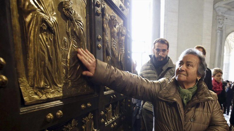 A woman touches the Holy Door in St. Peter's Basilica after Pope Francis opened it to mark the inauguration of the Jubilee Year of Mercy at the Vatican in this Dec. 8, 2015, file photo. Pope Francis has approved the theme "Pilgrims of Hope" to be the motto for the Holy Year 2025. (CNS photo/Max Rossi, Reuters)