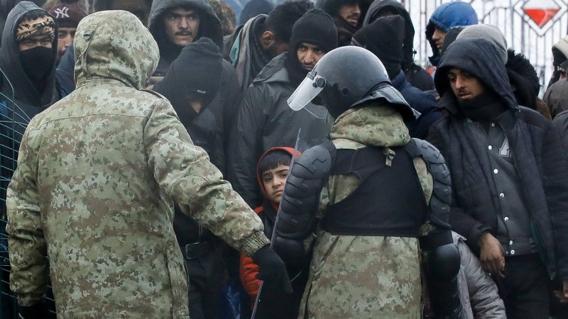 Belarusian law enforcement personnel stand next to immigrants in a camp near the Bruzgi-Kuznica checkpoint on the Belarusian-Polish border in the Grodno region of Belarus, in this Nov. 18, 2021, file photo. The Vatican announced Jan. 18 that Pope Francis has authorized 100,000 euros to support thousands of migrants stuck between the borders of Poland and Belarus. (CNS photo/Kacper Pempel, Reuters)