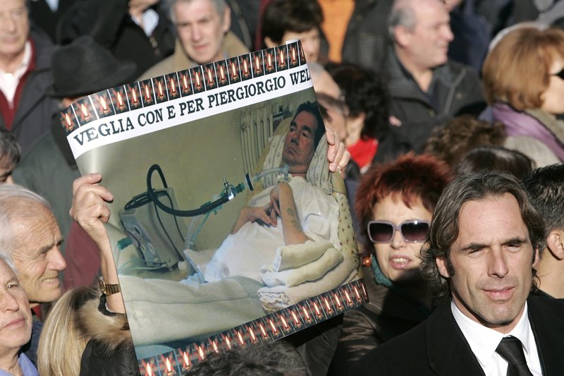 Mourners holds a picture of Piergiorgio Welby during his funeral in Rome in this Dec. 24, 2006, file photo. Welby, who suffered from advanced muscular dystrophy, died after his doctor switched off his life support system. On Feb. 15, 2022, Italy's Constitutional Court blocked a national referendum on legalizing euthanasia, saying it would violate constitutional protections of human life. (CNS photo/Max Rossi)