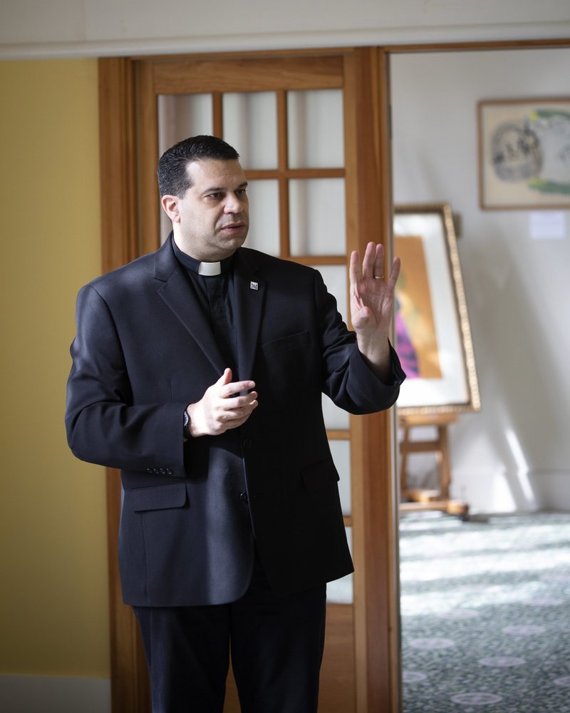 Sulpician Father Dominic Ciriaco, rector of Theological College in Washington, is seen Feb. 17, 2022, talking about an art exhibit he put together at the college titled "Beauty and the Priest: Preaching with the Artwork of Corita Kent." Kent's serigraphs, which include scriptural and social justice themes, are on display through March 3. (CNS photo/Tyler Orsburn)