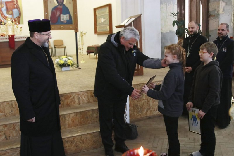 Cardinal Konrad Krajewski, the papal almoner, greets a girl as he and Archbishop Sviatoslav Shevchuk of Kyiv-Halych, left, head of the Eastern-rite Ukrainian Catholic Church, meet Ukrainian refugees in Lviv, Ukraine, March 10, 2022. (CNS photo/courtesy Ukrainian Catholic Church)